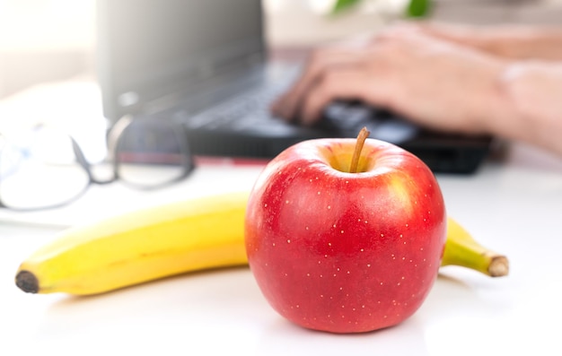 Foto una manzana roja y un plátano en el escritorio el concepto de una comida saludable en el trabajo primer plano foco selectivo