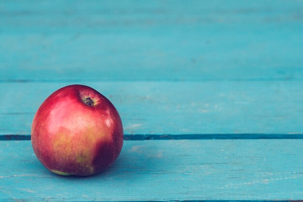 Una manzana roja sobre una mesa de madera azul. Copia espacio