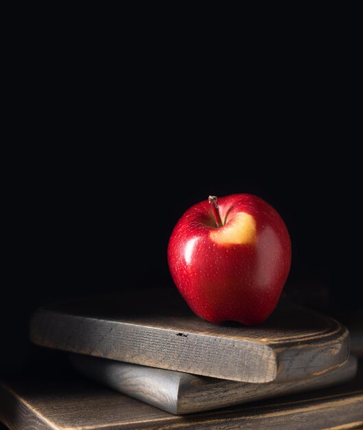 Una manzana roja sobre tablas de madera en una llave oscura Enfoque selectivo