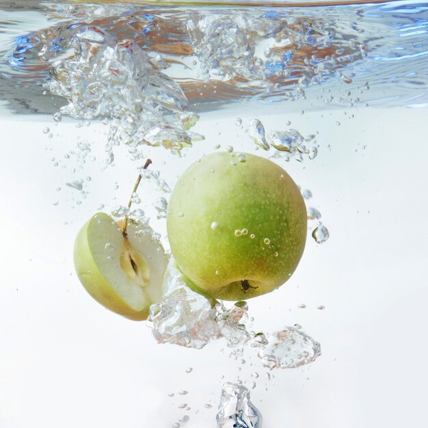 Manzana verde bajo el agua con un rastro de burbujas transparentes