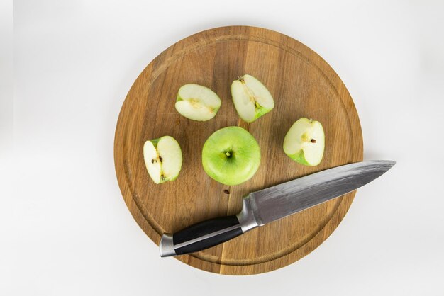 Foto manzana verde cortada en una tabla de madera sobre un fondo blanco vista desde arriba una manzana y un cuchillo están en la tabla