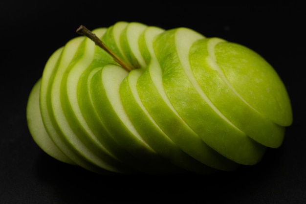 Manzana verde fresca y en rodajas aisladas sobre fondo negro concepto abstracto de arte