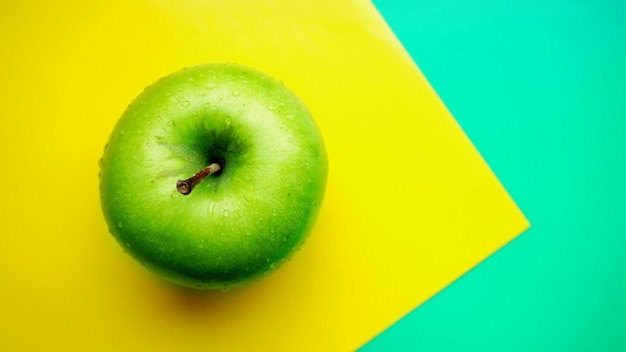 Manzana verde en gotas de agua sobre fondo de color amarillo aislado cerrar vista superior macro