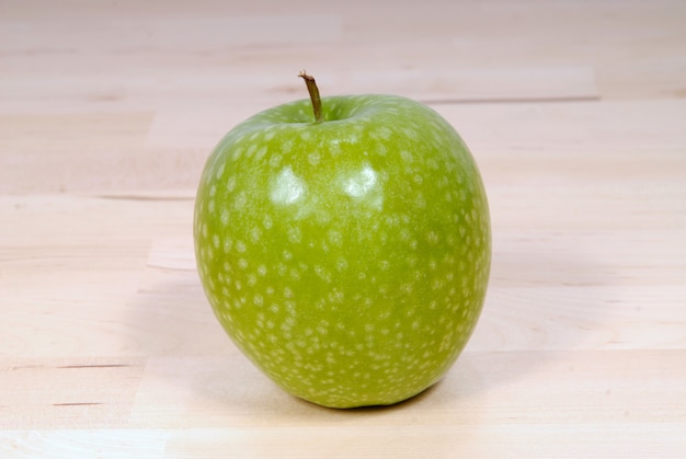 Manzana verde de granito sobre una mesa de madera