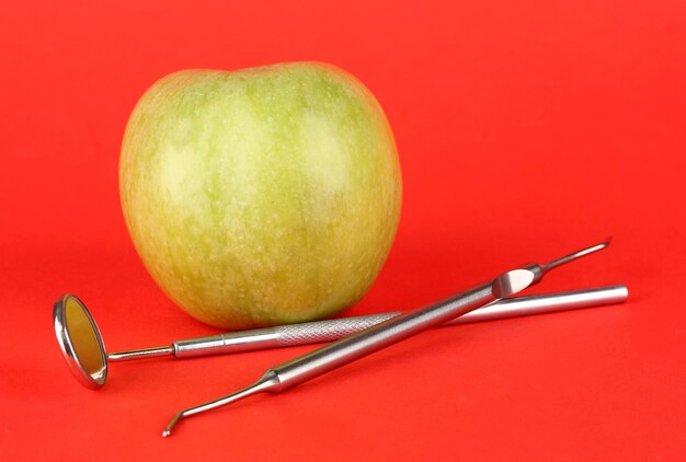 Foto manzana verde y herramientas dentales sobre fondo de color