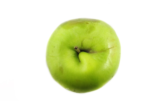 Una manzana verde con un lado podrido de caer sobre un fondo blanco. Fruta.