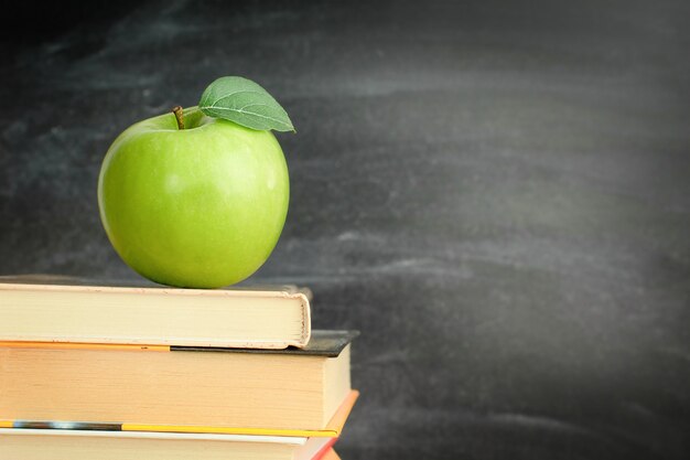 Una manzana verde en libros en el aula.