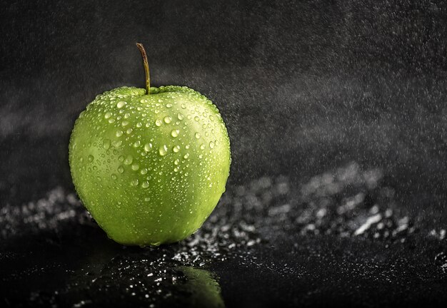 Manzana verde en mesa oscura