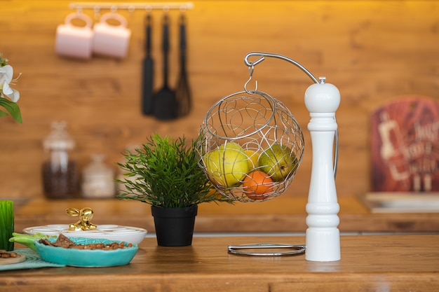 Manzana verde, pera y mandarina están en un jarrón de metal y una hierba verde en la cocina.