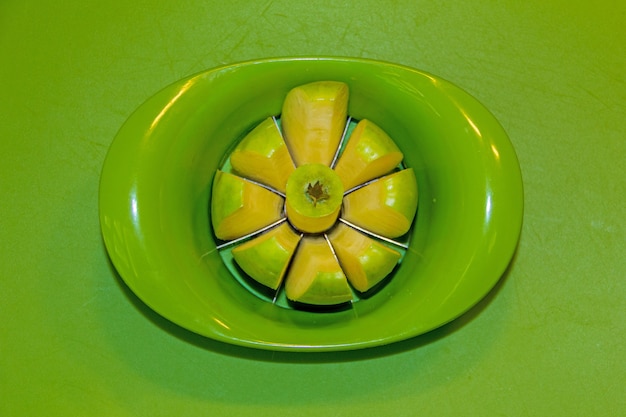 Foto manzana verde en un plato verde cortado en rodajas, sobre una mesa verde vista cercana