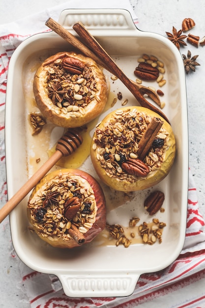 Manzanas al horno con granola, arándanos, nueces y miel en una fuente para horno.