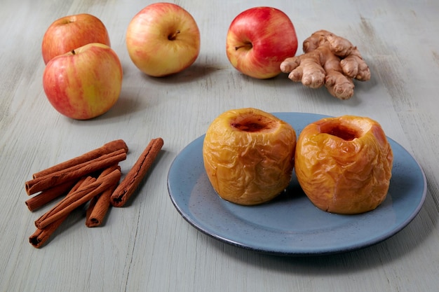 Manzanas al horno en un plato azul con miel, canela y jengibre en una mesa de madera clara Receta casera