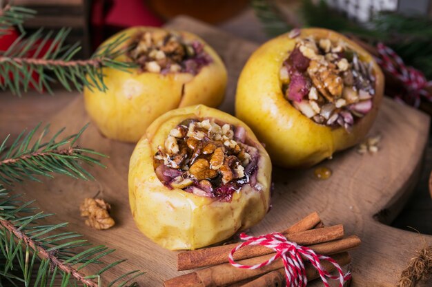 Manzanas al horno rellenas de bayas, nueces y miel sobre una tabla de cortar de madera.