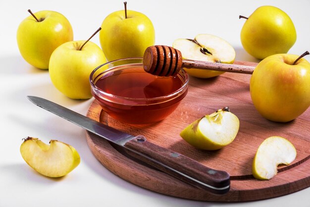 Las manzanas amarillas frescas, maduras y cortadas con miel se encuentran en la mesa.