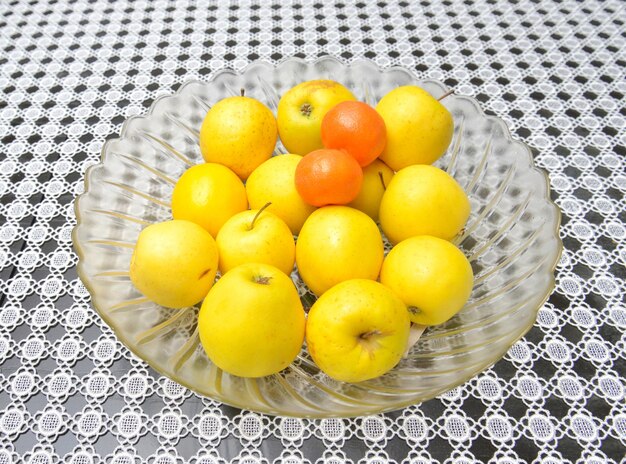 Foto manzanas amarillas y mandarinas en un cuenco de vidrio grande en una imagen de mesa de un
