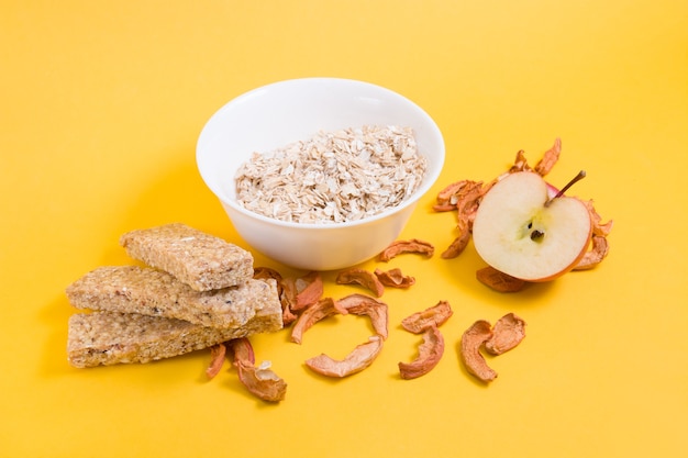 manzanas, avena y barras de avena sobre fondo amarillo