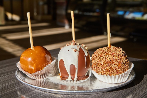 Manzanas de caramelo gourmet con coberturas en una bandeja de plata