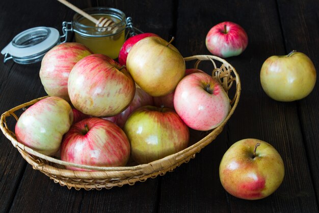 Manzanas en una cesta y miel sobre un fondo negro