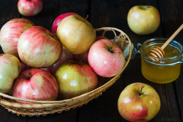 Manzanas en una cesta y miel sobre un fondo negro