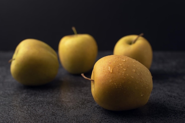 Manzanas doradas maduras con gotas de agua sobre un fondo oscuro