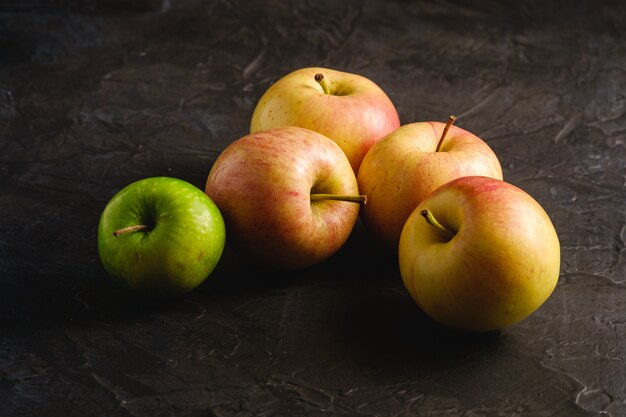 Manzanas dulces frescas sobre una superficie con textura negra oscura, ángulo de visión