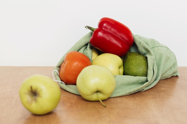 Manzanas frescas aguacate tomates pimienta en bolsa de algodón sobre mesa de madera Cero desperdicio de compras