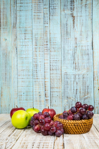 Foto manzanas frescas con uvas rojas sobre fondo de madera