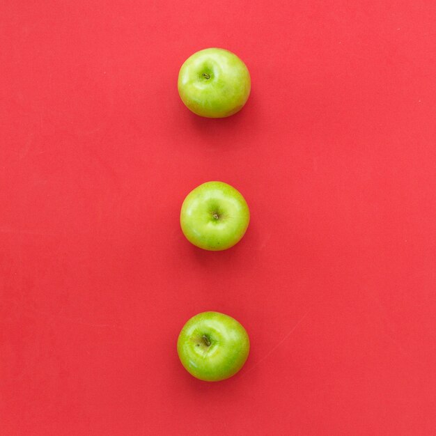 Manzanas frescas verdes sobre superficie roja