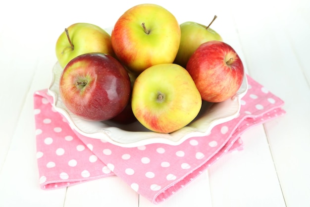 Manzanas jugosas en un plato sobre una mesa de madera blanca