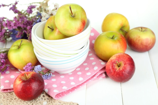 Foto manzanas jugosas en un plato sobre una mesa de madera blanca