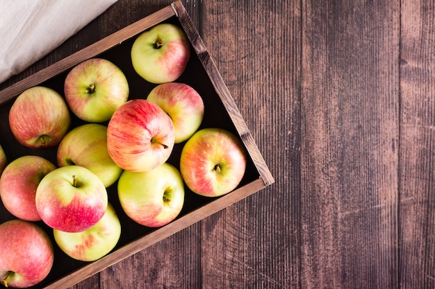 Manzanas maduras frescas en una caja sobre una mesa de madera Frutas locales de temporada Vista superior