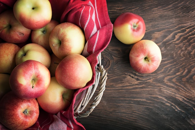 Manzanas maduras frescas en la cesta en la mesa de madera