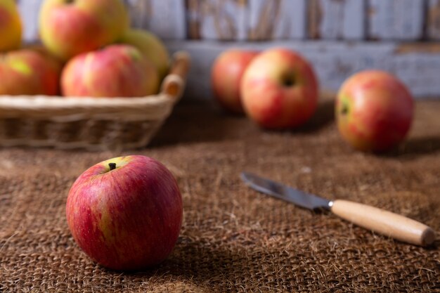 Manzanas maduras sobre arpillera y en una canasta. Estilo rústico