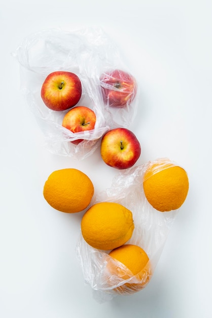 Manzanas naranjas maduras frescas en bolsas de plástico transparentes sobre un fondo blanco Vista superior plana