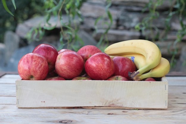 Manzanas y plátanos en una caja sobre una mesa