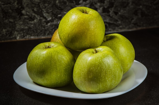 Manzanas en un plato sobre un fondo gris