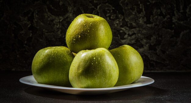 Manzanas en un plato sobre un fondo gris