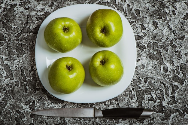 Manzanas en un plato sobre un fondo gris