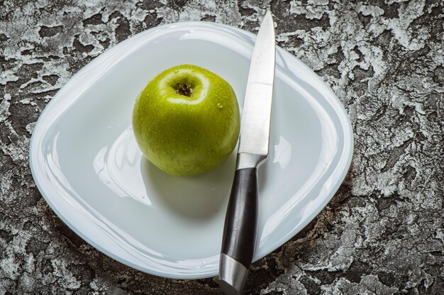 Manzanas en un plato sobre un fondo gris