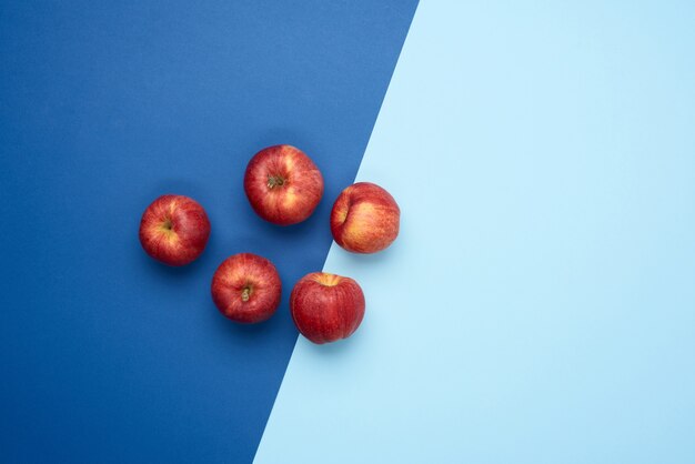 Manzanas redondas maduras rojas se encuentran sobre un fondo azul.