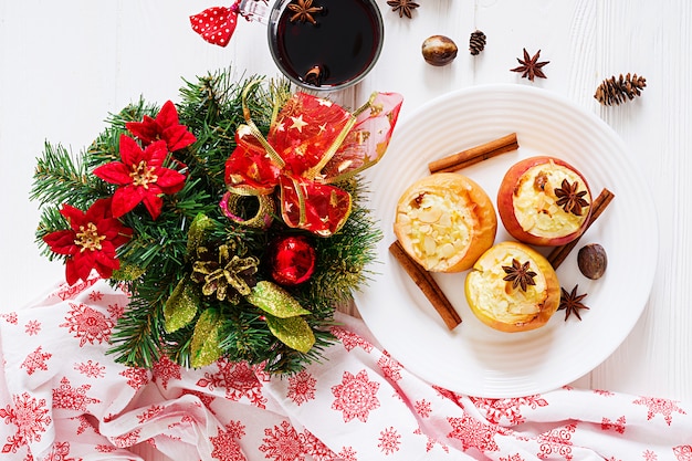 Manzanas rellenas al horno con queso cottage, pasas y almendras para Navidad en una mesa blanca. Postre de comida de Navidad.