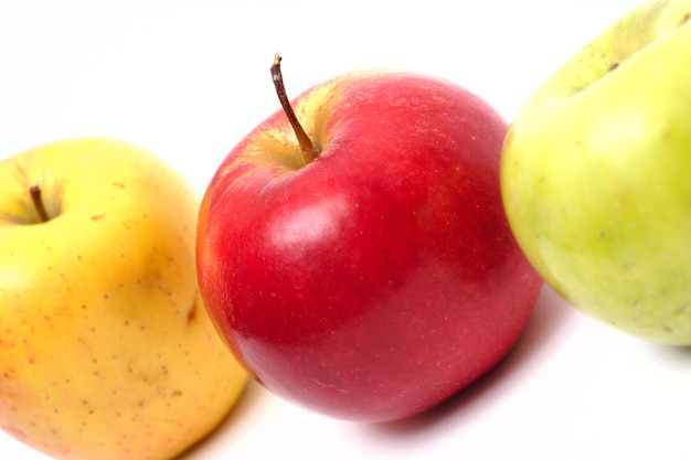 Manzanas rojas, amarillas y verdes seguidas en un fondo blanco