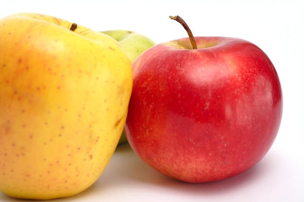 Manzanas rojas, amarillas y verdes sobre un fondo blanco.