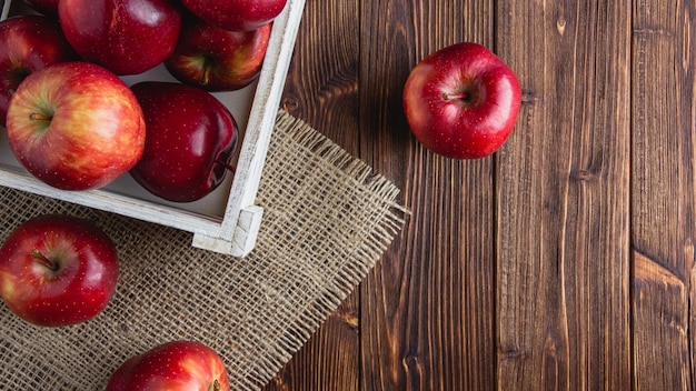 Manzanas rojas en una caja sobre un fondo de madera