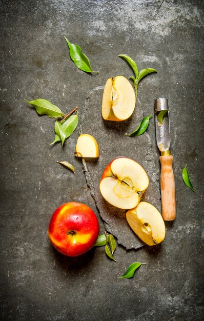 Manzanas rojas frescas con hojas y cuchillo sobre un fondo de piedra. Vista superior