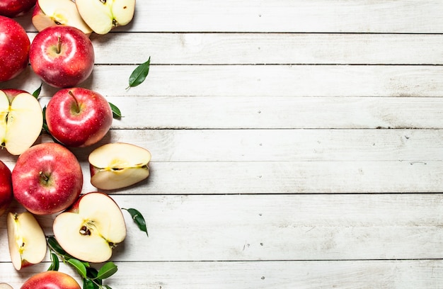 Manzanas rojas frescas con hojas. sobre un fondo de madera blanca.