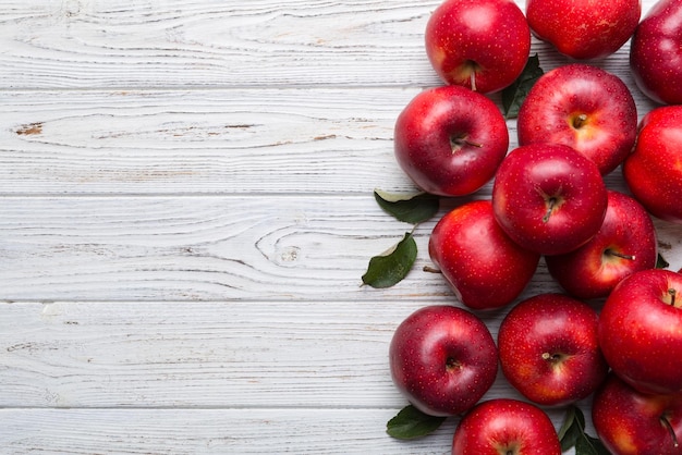 Manzanas rojas frescas con hojas verdes en la mesa de madera Sobre fondo de madera Vista superior espacio libre para texto