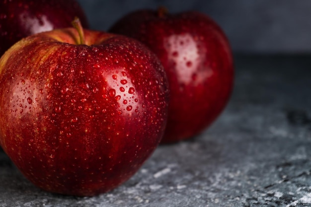 Manzanas rojas frescas húmedas y jugosas con gotas de agua sobre fondo oscuro con espacio de copia Enfoque selectivo