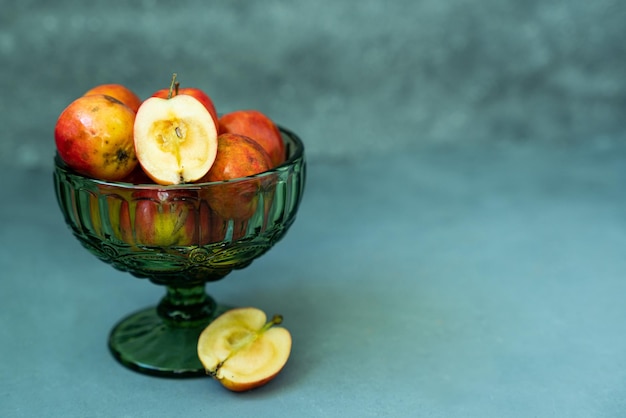 Manzanas rojas frescas en un jarrón de cristal sobre un fondo gris