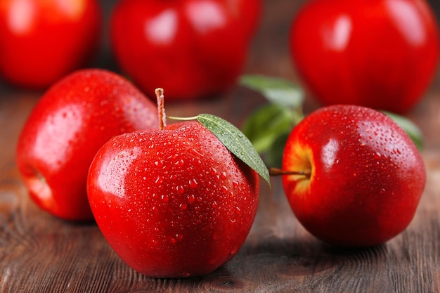 Manzanas rojas con gotas en primer plano de la mesa de madera